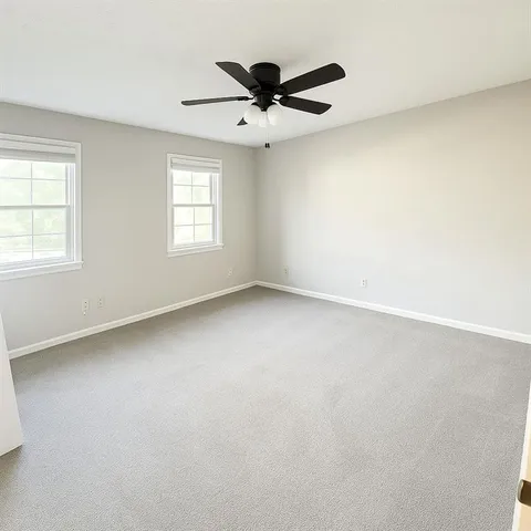 an empty room with a ceiling fan and window