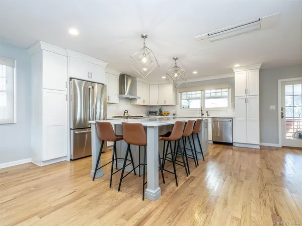 a kitchen with stainless steel appliances a dining table chairs stove refrigerator and cabinets