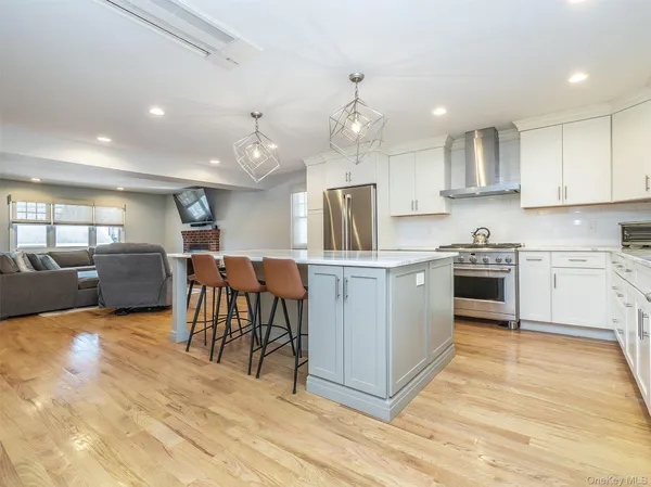 a kitchen with kitchen island granite countertop wooden floors stainless steel appliances and white cabinets