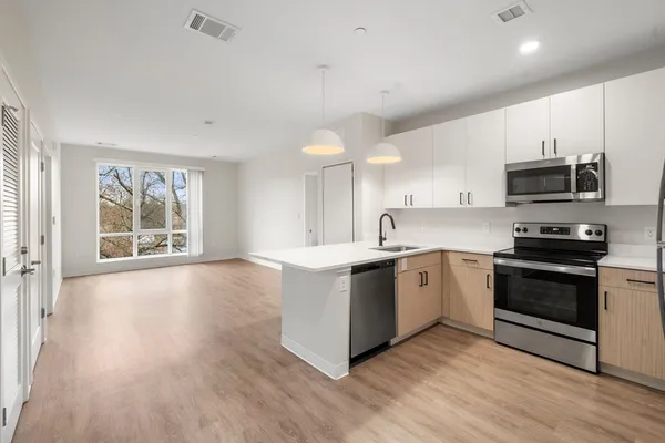 a large kitchen with stainless steel appliances granite countertop a stove top oven a sink dishwasher a microwave oven and a cabinets with wooden floor