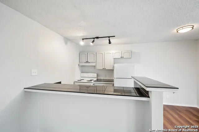 a kitchen with kitchen island a sink a stove and white cabinets