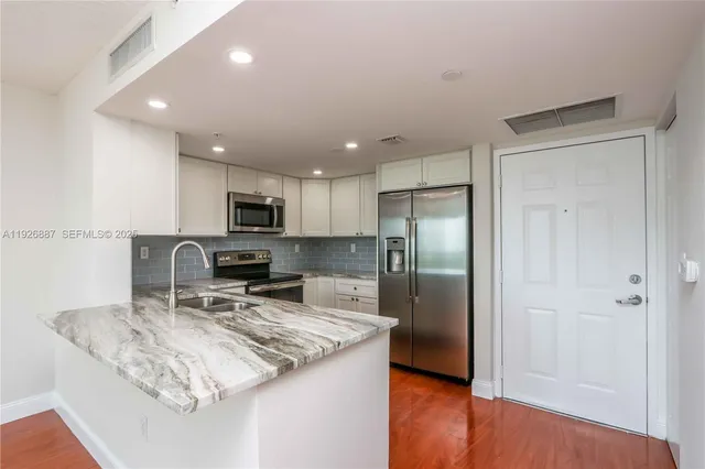 a kitchen with stainless steel appliances granite countertop a sink refrigerator and microwave