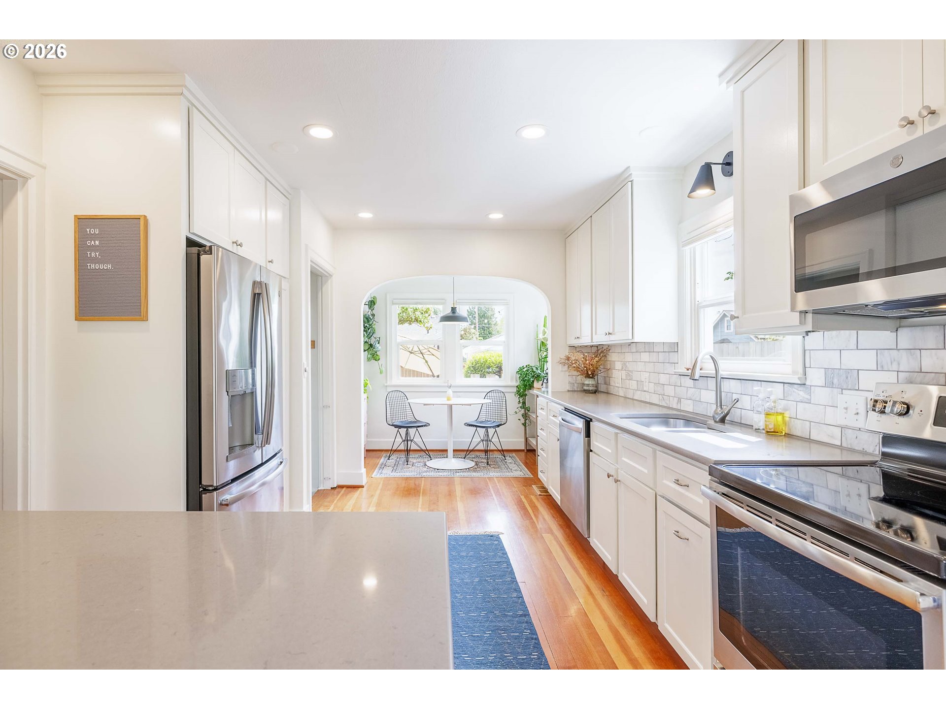 6128 North Denver Avenue Portland, OR 97217 - Photo 11 of 32 a kitchen with stainless steel appliances granite countertop a refrigerator a sink dishwasher and white cabinets with wooden floor