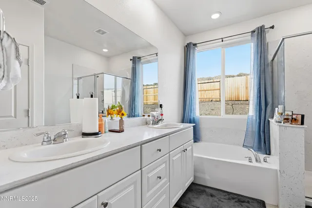 a bathroom with double vanity sinks a large mirror and a bathtub