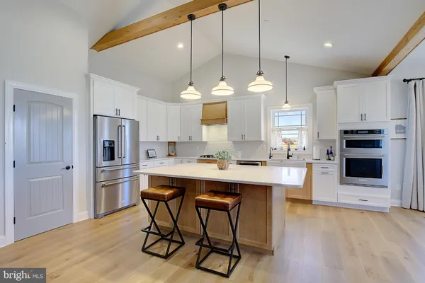 a kitchen with kitchen island a stove a sink a refrigerator and a dining table with wooden floor