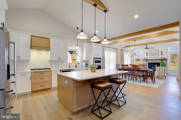 a kitchen with kitchen island a dining table chairs stainless steel appliances and cabinets