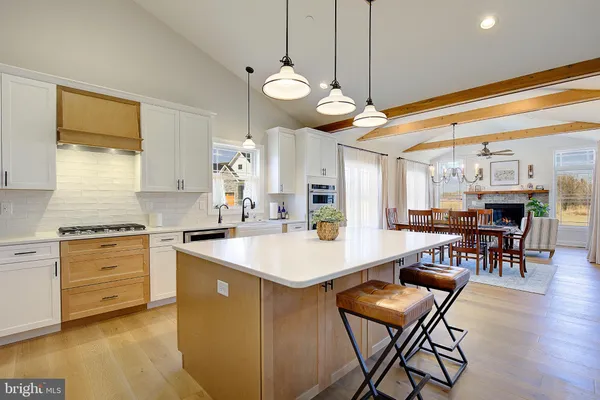 a large kitchen with stainless steel appliances a stove a sink a dining table and chairs with wooden floor
