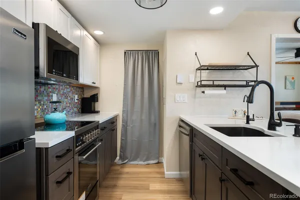 a kitchen with stainless steel appliances granite countertop a sink a stove and a refrigerator