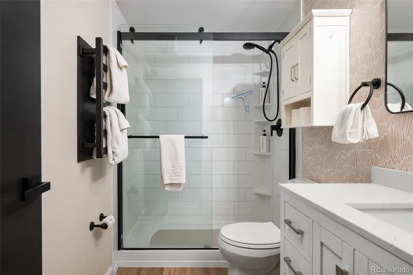 a bathroom with a granite countertop shower sink vanity and toilet