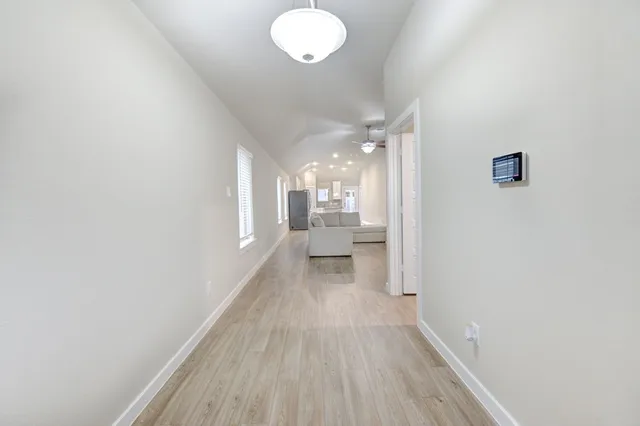 a view of a hallway with wooden floor and a chandelier