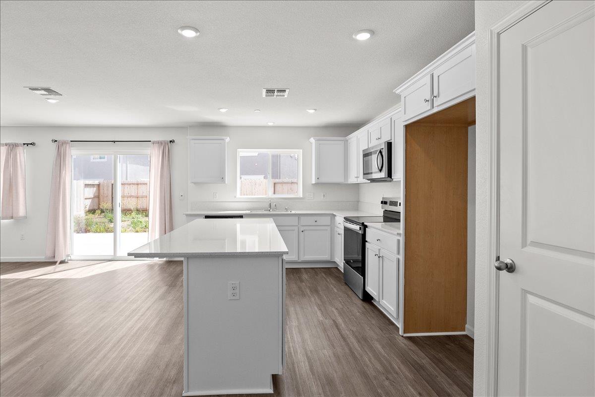 18462 Waterfront Way Lathrop, CA 95330 - Photo 5 of 50 a kitchen with a refrigerator a sink and wooden floor