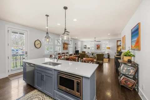 a kitchen with stainless steel appliances granite countertop a sink a stove and a wooden floor