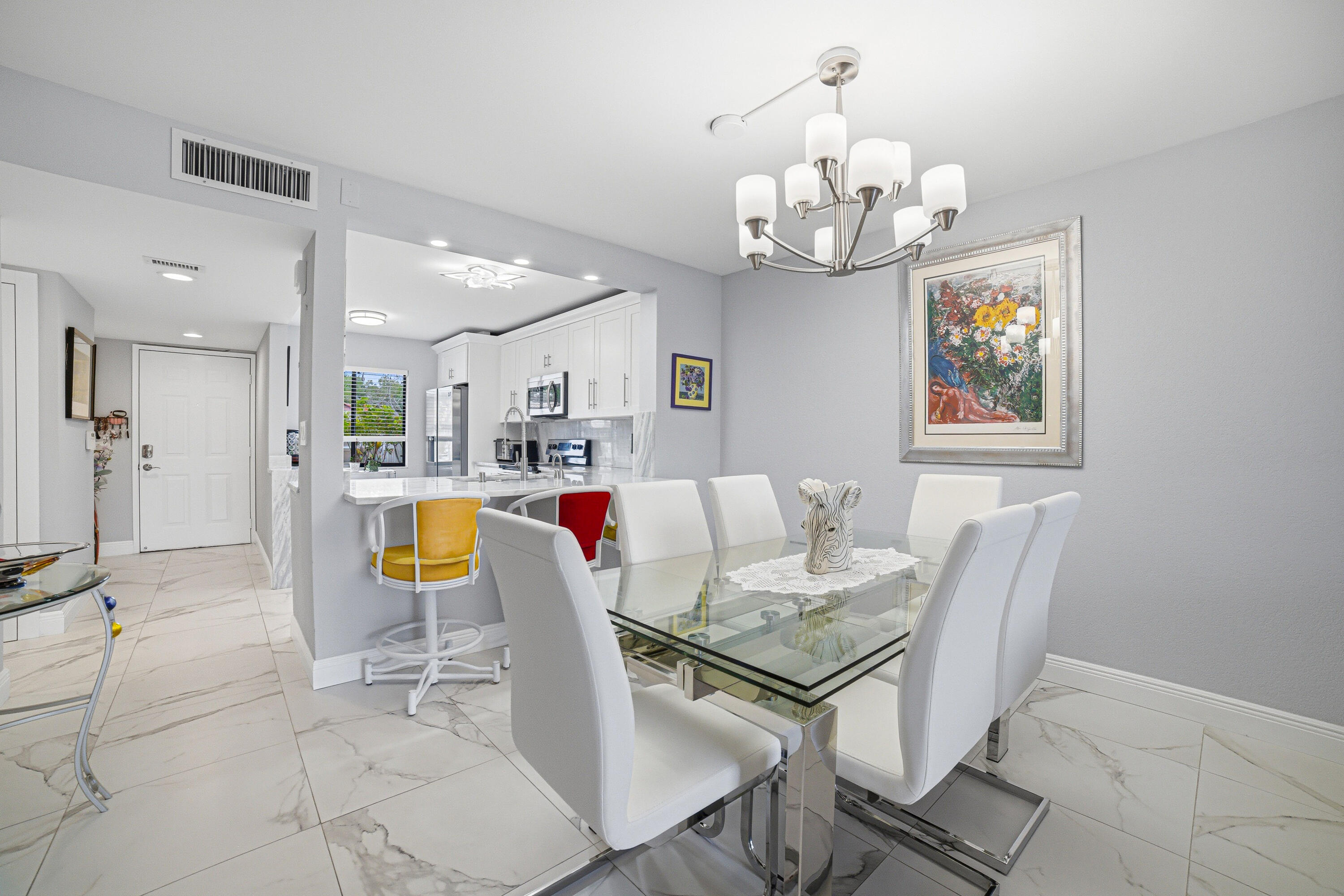 6149 Pointe Regal Circle, Unit 104 Delray Beach, FL 33484 - Photo 11 of 64 a dining room with wooden floor a chandelier a wooden table and chairs