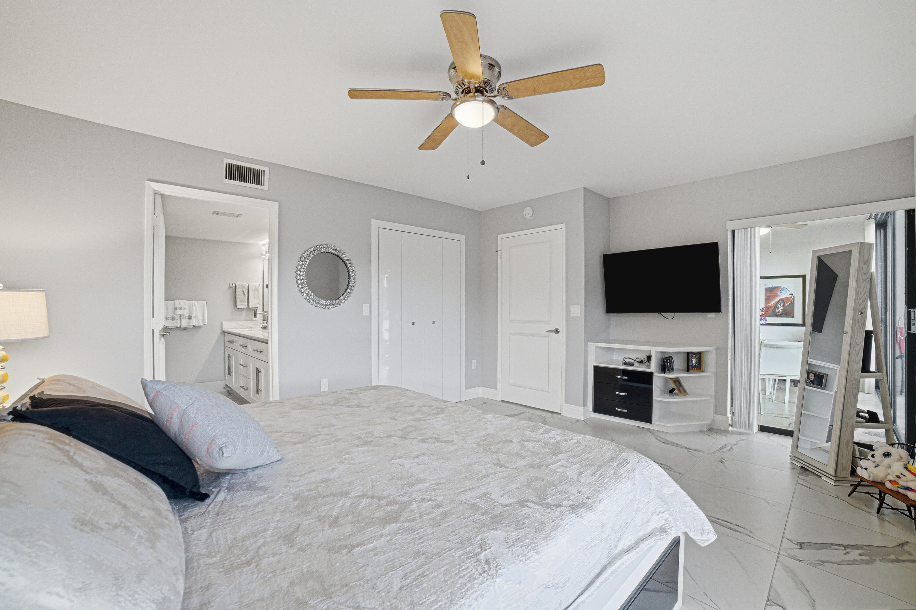 6149 Pointe Regal Circle, Unit 104 Delray Beach, FL 33484 - Photo 19 of 64 a spacious bedroom with a bed and a flat screen tv