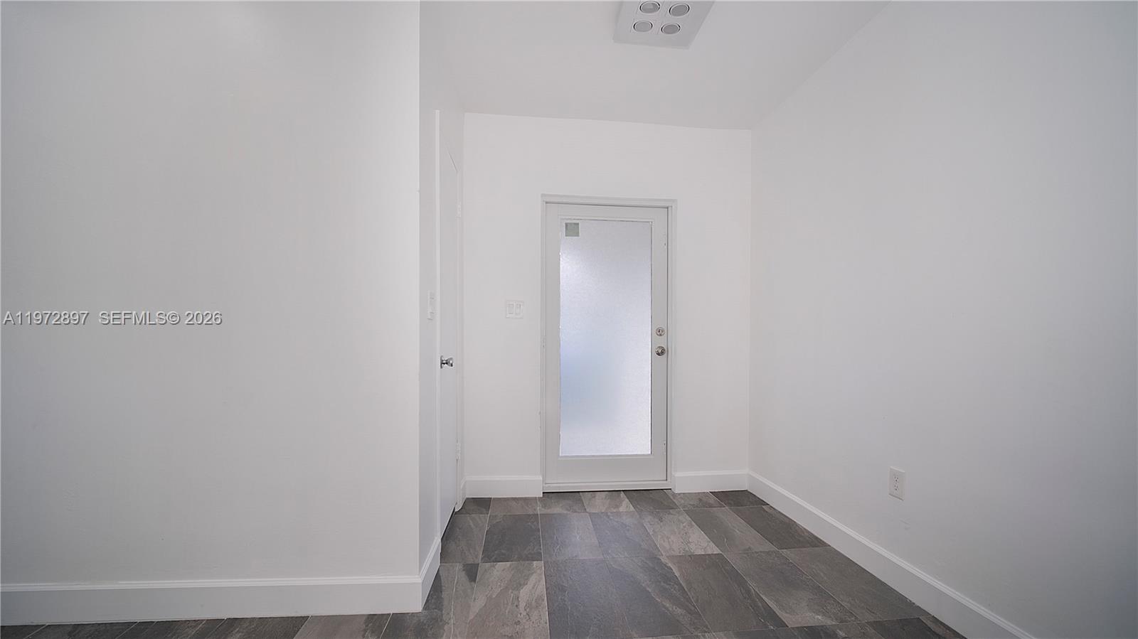 11690 Southwest 81st Road, Unit 11690 Pinecrest, FL 33156 - Photo 4 of 26 a view of an empty room with wooden floor and a window