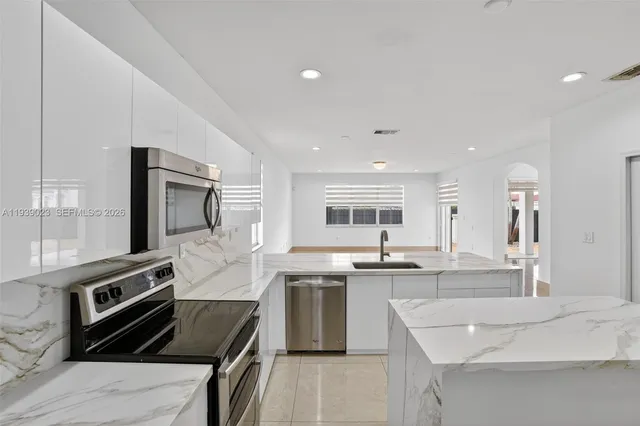 a kitchen with stainless steel appliances kitchen island granite countertop a sink stove and refrigerator