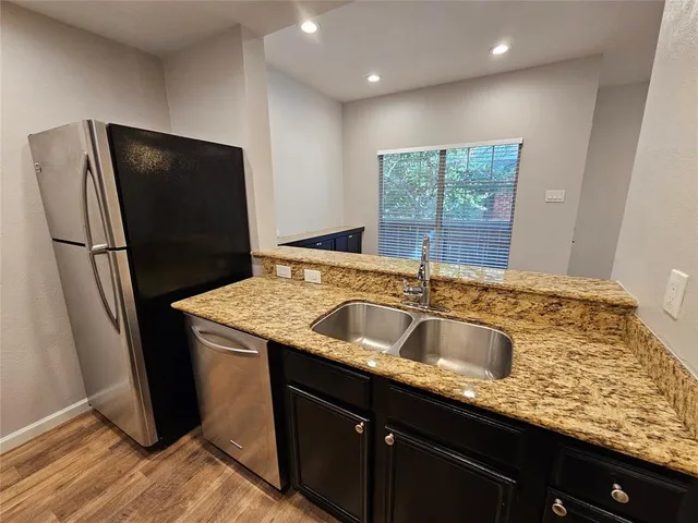 a kitchen with granite countertop a refrigerator and a sink