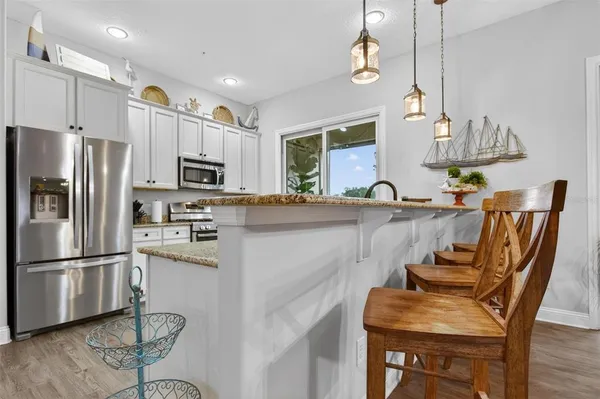 a kitchen with granite countertop a table chairs microwave and refrigerator