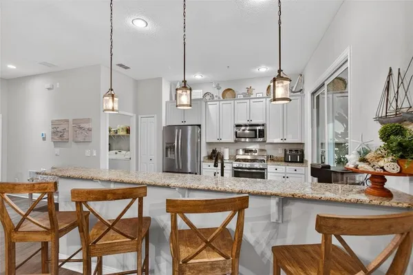 a kitchen with stainless steel appliances granite countertop a stove a sink island and chairs