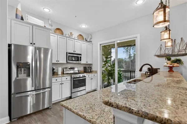 a kitchen with stainless steel appliances granite countertop a refrigerator a stove a sink a microwave and island