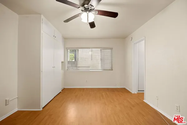 a view of empty room with wooden floor and fan
