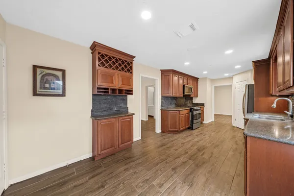 a kitchen with stainless steel appliances granite countertop wooden cabinets a stove top oven a sink and dishwasher with wooden floor
