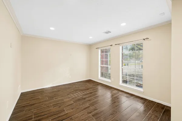 a view of an empty room with wooden floor and a window