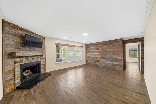 a view of an empty room with wooden floor fireplace and a window