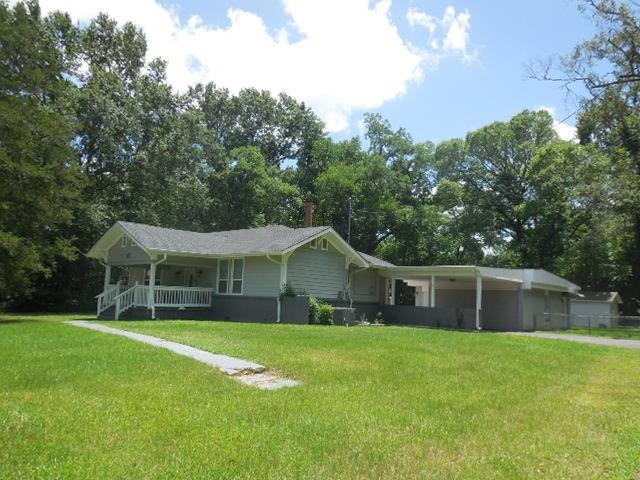 Ranch-style home with a porch, a front yard, and view of scattered trees