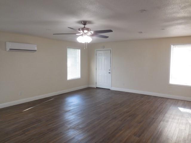 127 Stonewall-Preston Road Stonewall, LA 71078 - Photo 17 of 19 Spare room featuring a wall mounted air conditioner, a ceiling fan, baseboards, and dark wood-style flooring