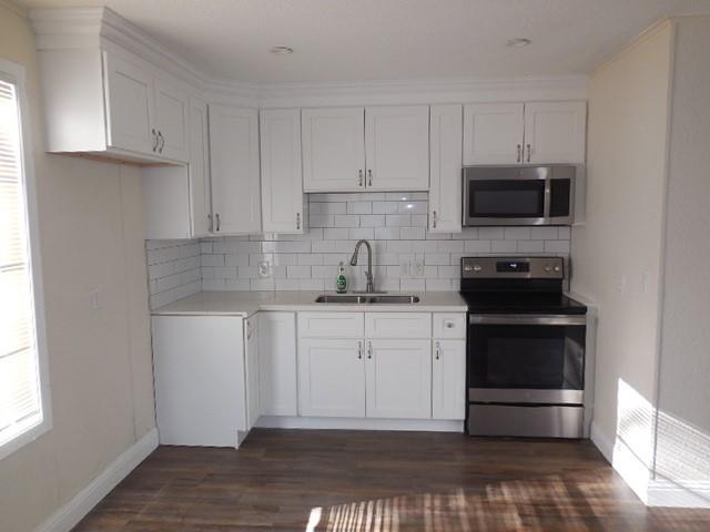 127 Stonewall-Preston Road Stonewall, LA 71078 - Photo 18 of 19 Kitchen with white cabinets, a sink, backsplash, light countertops, and appliances with stainless steel finishes