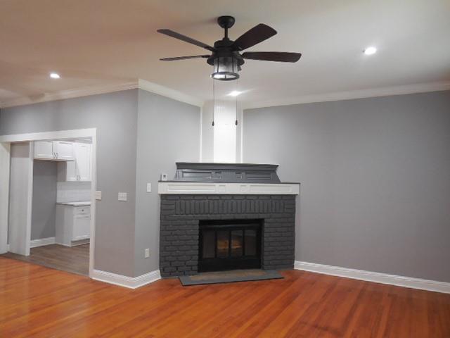 127 Stonewall-Preston Road Stonewall, LA 71078 - Photo 5 of 19 Unfurnished living room with ceiling fan, ornamental molding, a brick fireplace, and light wood-style flooring