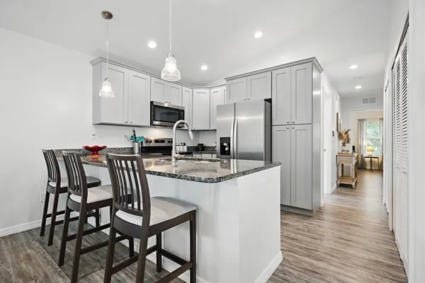 a kitchen with kitchen island granite countertop a refrigerator and a stove top oven