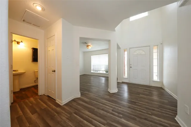 a view of an empty room with wooden floor and a bathroom