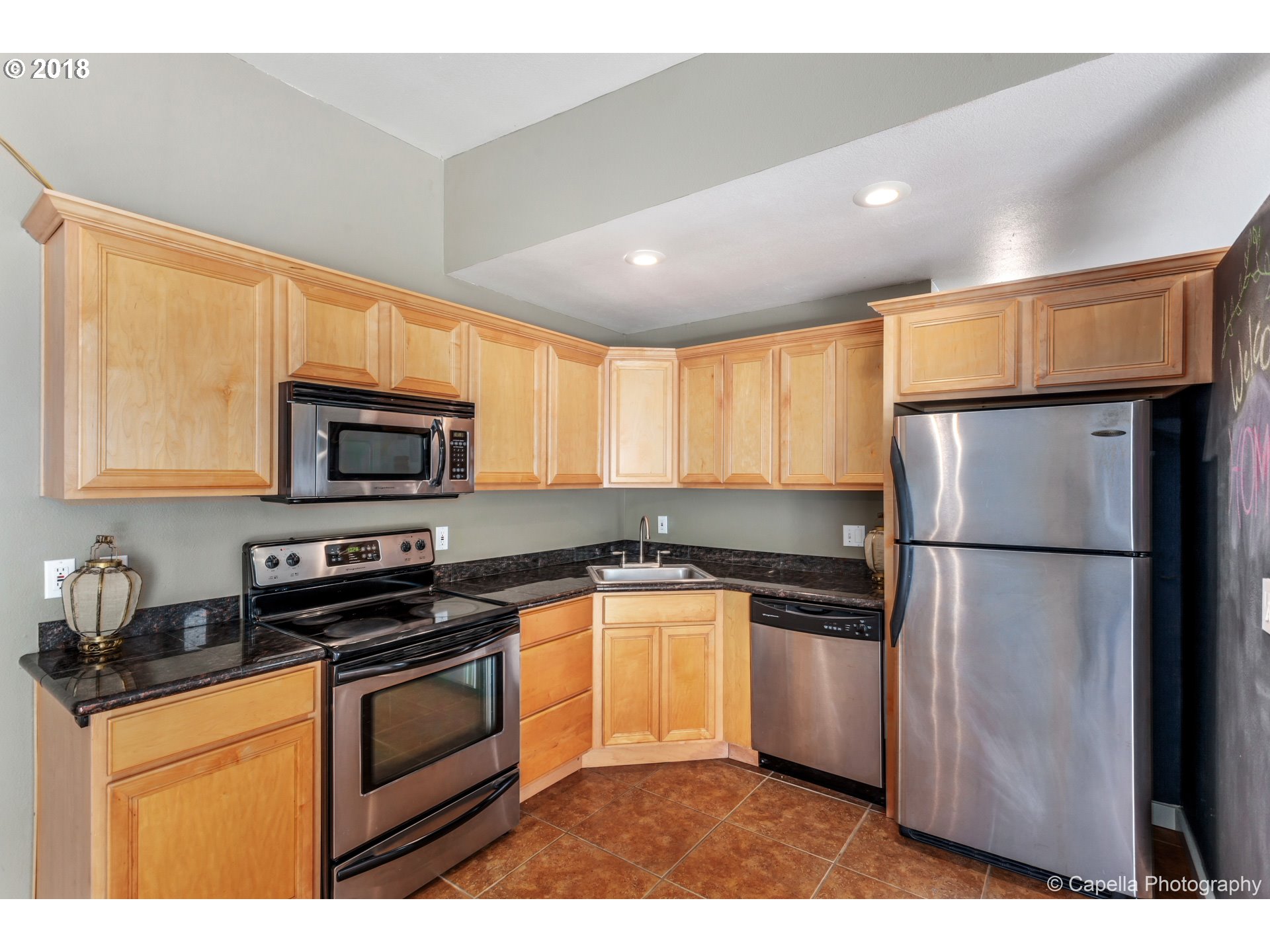 6220 Southwest Capitol Highway, Unit 8 Portland, OR 97239 - Photo 9 of 13 a kitchen with stainless steel appliances granite countertop a refrigerator a stove a sink and a microwave