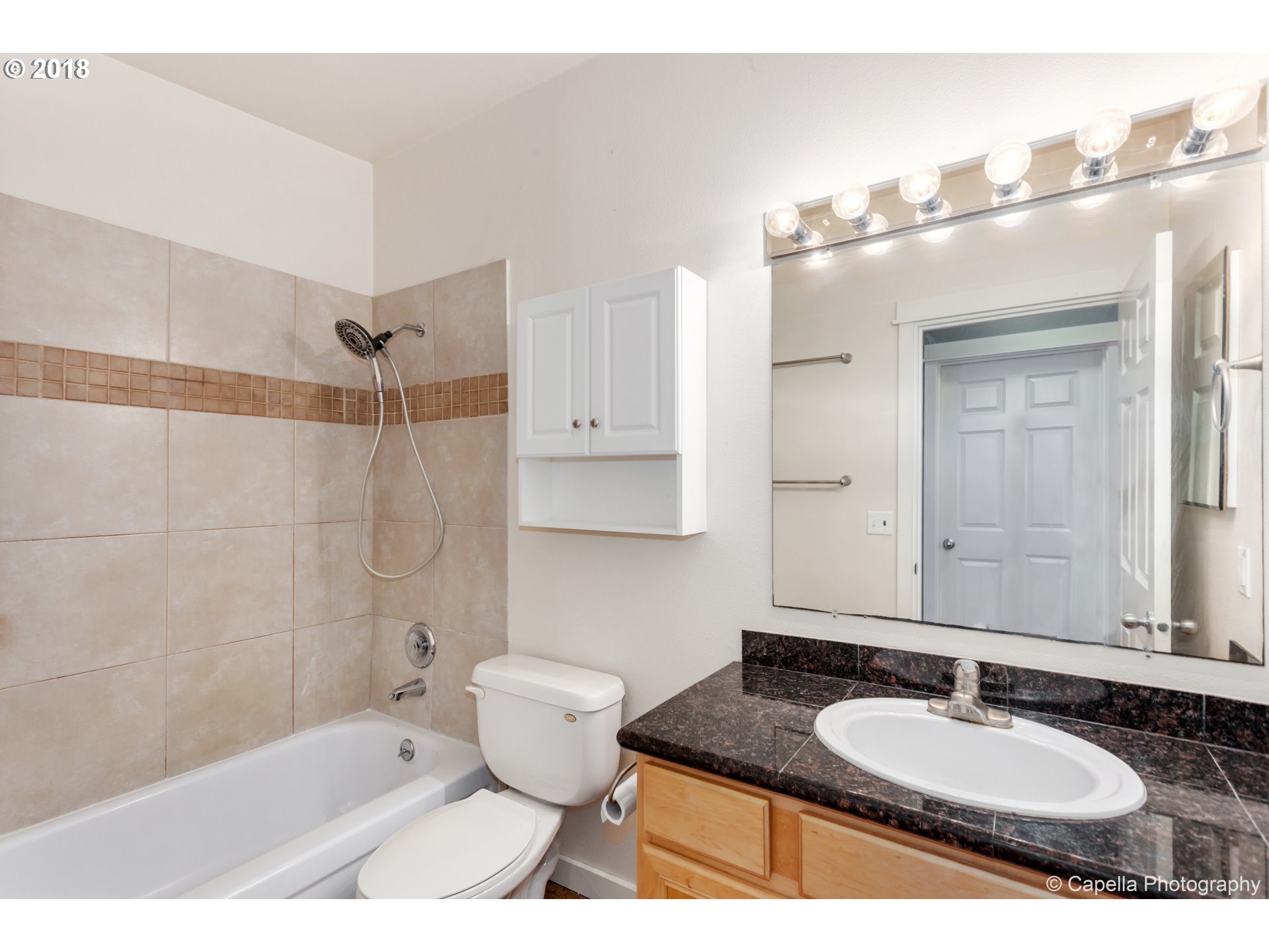 6220 Southwest Capitol Highway, Unit 8 Portland, OR 97239 - Photo 10 of 13 a bathroom with a granite countertop sink a toilet a mirror and bathtub