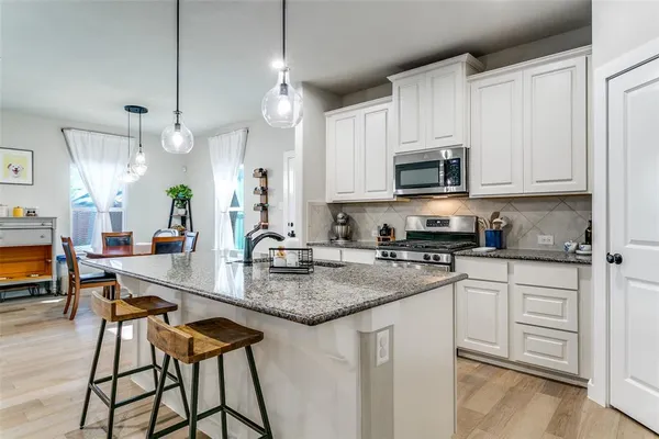 a kitchen with stainless steel appliances granite countertop a sink a stove a microwave a center island and cabinets