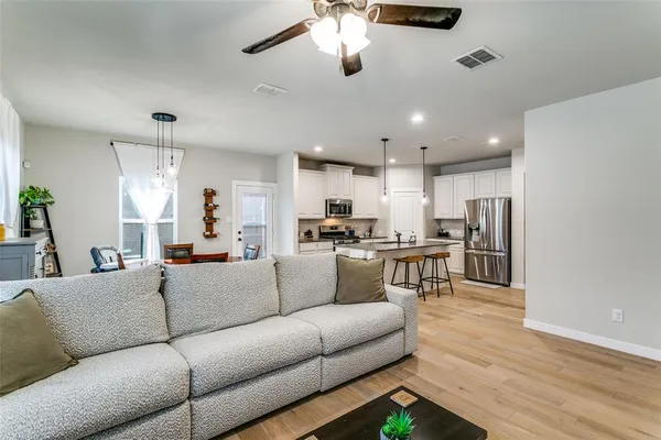 a living room with furniture kitchen view and a chandelier