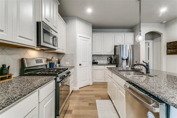 a kitchen with stainless steel appliances granite countertop a stove a sink and a refrigerator
