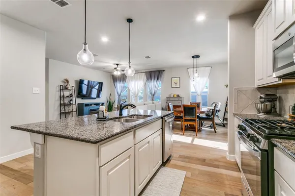 a kitchen with stainless steel appliances granite countertop a sink a stove and a wooden floors