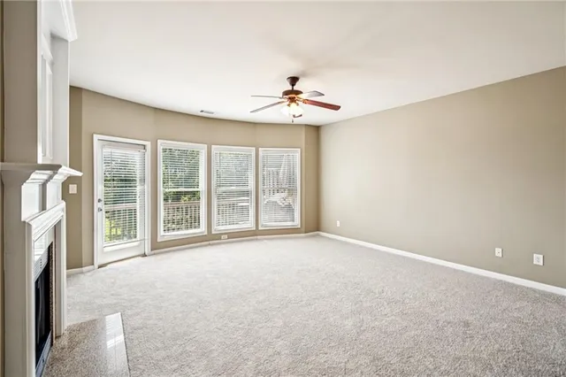 an empty room with windows and ceiling fan