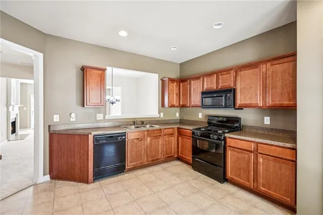 a kitchen with stainless steel appliances granite countertop wooden cabinets a sink dishwasher a stove and a refrigerator