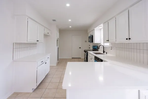 a large white kitchen with cabinets