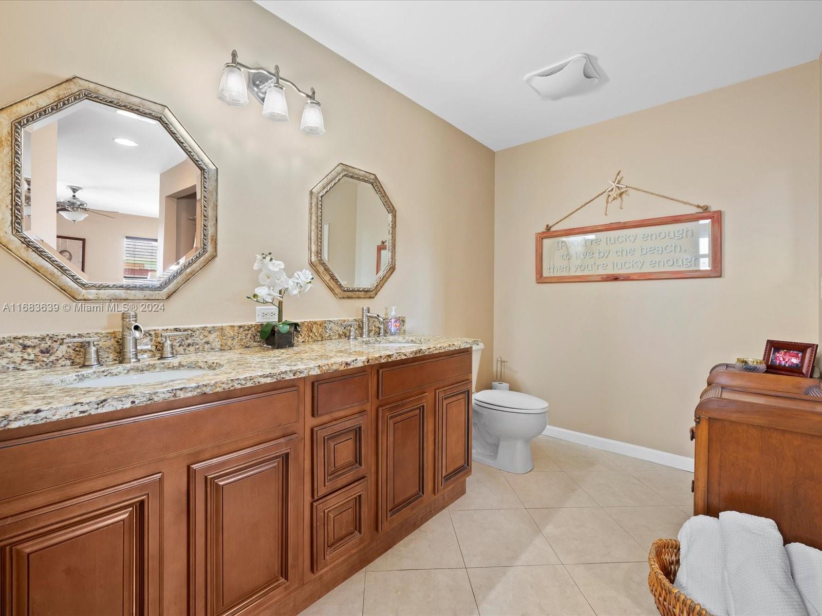 368 Church Road Tequesta, FL 33469 - Photo 18 of 20 a bathroom with a granite countertop toilet a sink and a mirror
