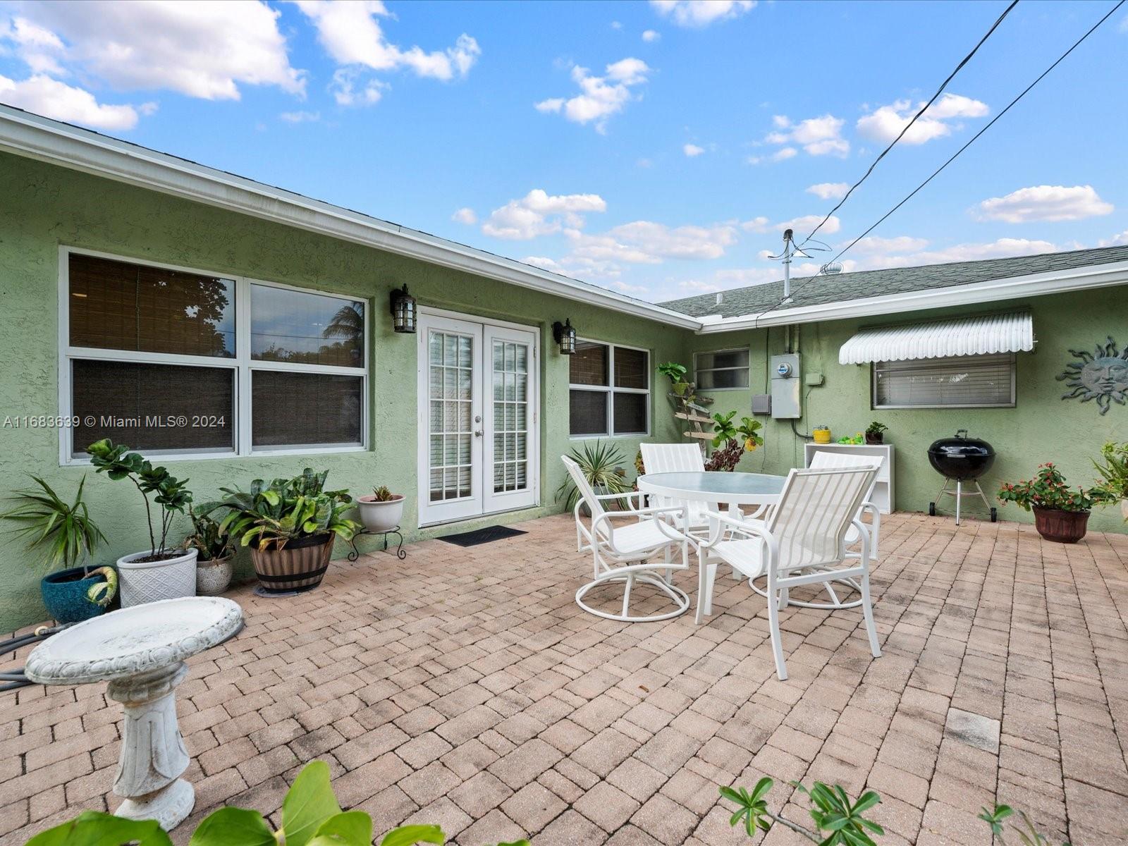 368 Church Road Tequesta, FL 33469 - Photo 4 of 20 a view of a patio with table and chairs potted plants and wooden fence