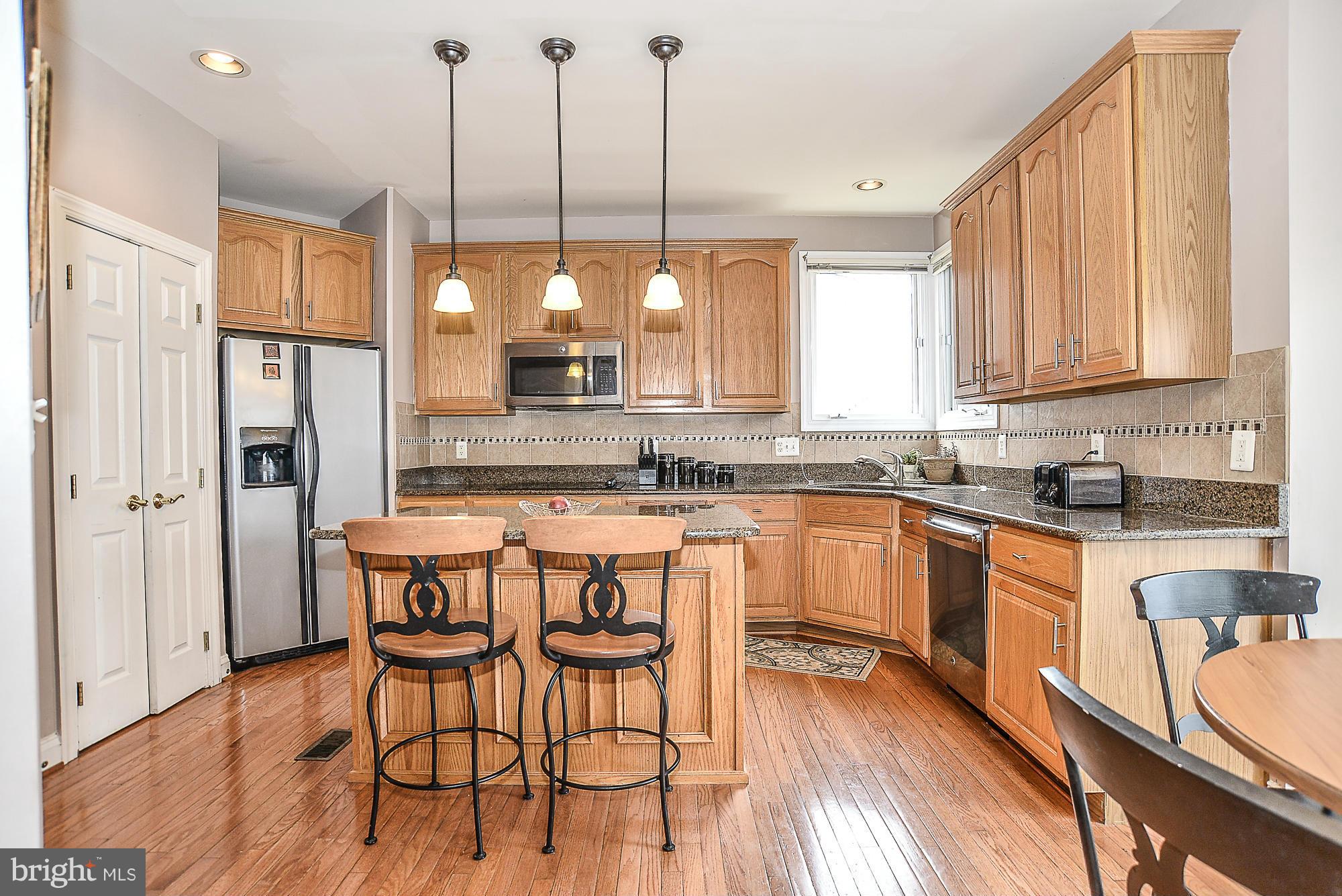 8747 Center Road Springfield, VA 22152 - Photo 11 of 30 a kitchen with stainless steel appliances granite countertop wooden floor window and white cabinets