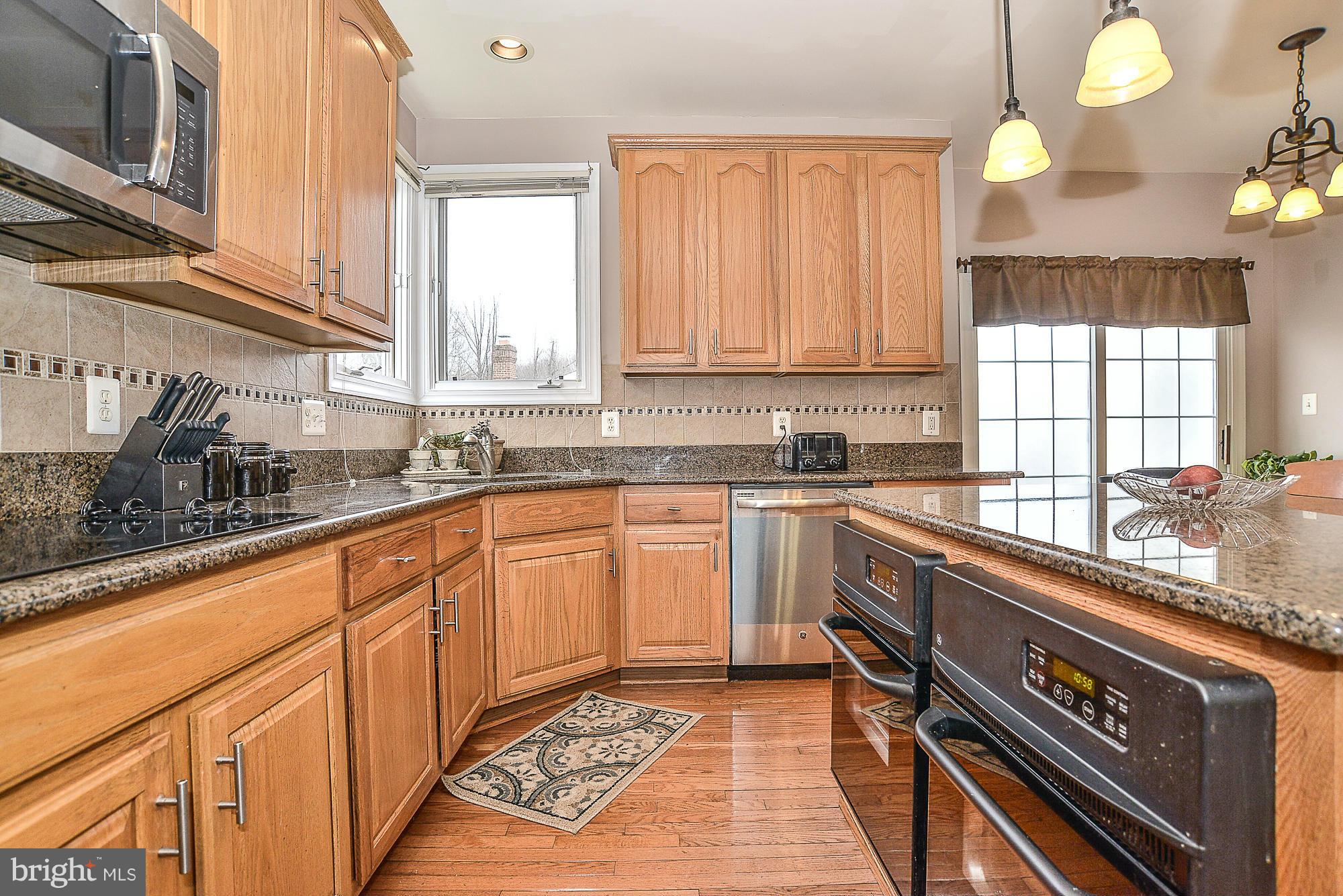 8747 Center Road Springfield, VA 22152 - Photo 12 of 30 a kitchen with granite countertop a sink a stove cabinets and wooden floor