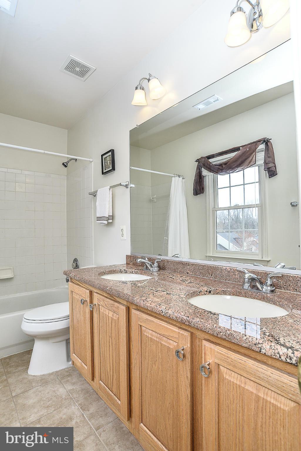 8747 Center Road Springfield, VA 22152 - Photo 22 of 30 a bathroom with a granite countertop sink a toilet a mirror and bathtub