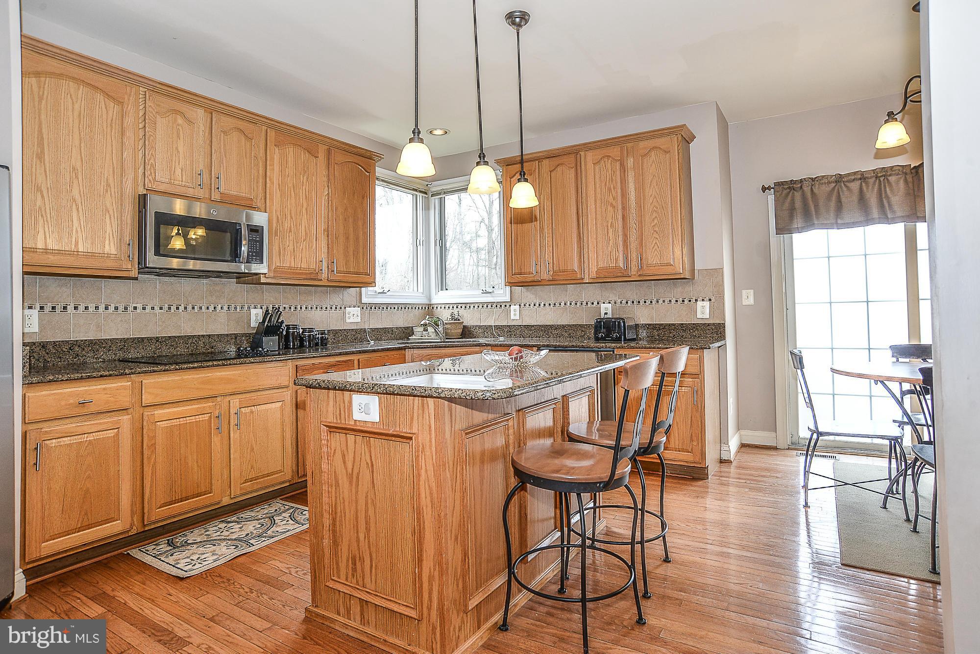 8747 Center Road Springfield, VA 22152 - Photo 9 of 30 a kitchen with stainless steel appliances granite countertop wooden cabinets a stove a sink dishwasher and a microwave oven with wooden floor