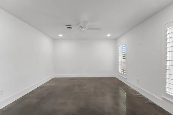 an empty room with windows and ceiling fan